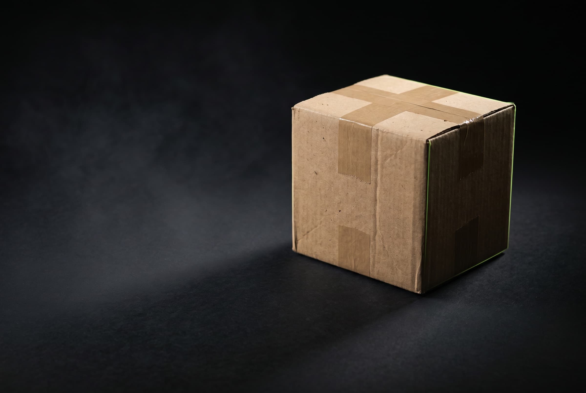 A kraft shipping parcel lit dramatically against a dark background